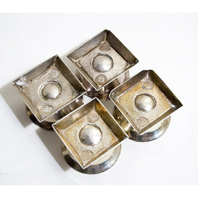 Four William Spratling silver salt dishes showing the bottoms with his artist stamp.