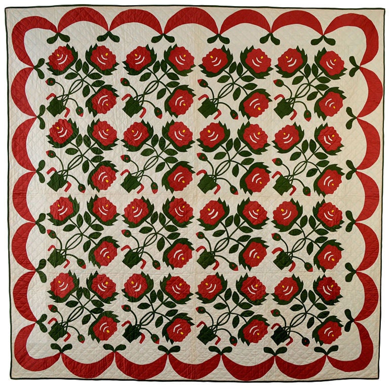 Cream colored antique quilt with bright red ribbon around the border and pots of red flowers in the center.