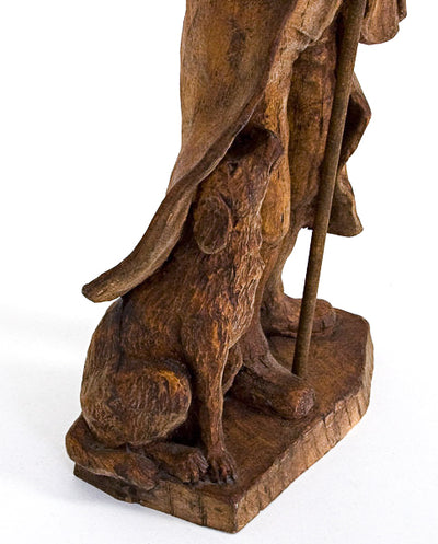 Close up of a wood carved dog sitting next to his master.