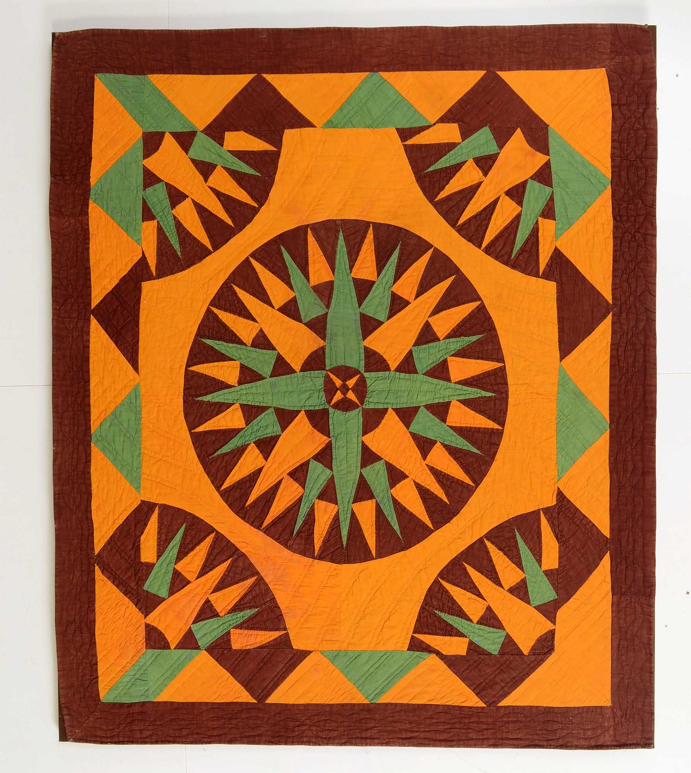 Orange brown and green antique Mariner's Compass Crib Quilt from Pennsylvania with central compass framed with quarter compasses and a triangle border.