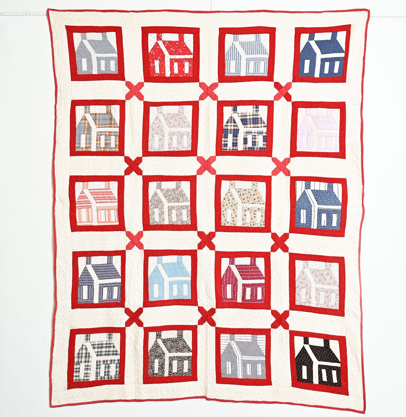 White and red antique quilt with schoolhouse patches in a variety of colors.
