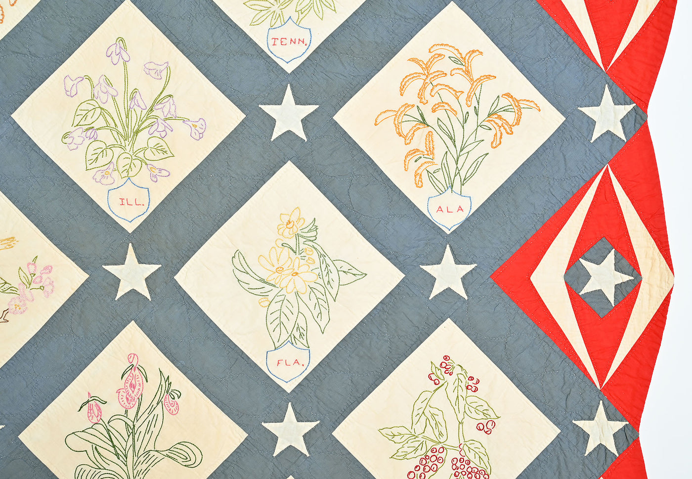 Detail view of embroidered state flowers and red border on quilt #1017. 
