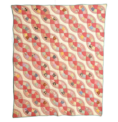 Antique Snail Trail Quilt with pinks and whites with green edging.